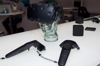 Vive Pre headset and two controllers in front of base stations.